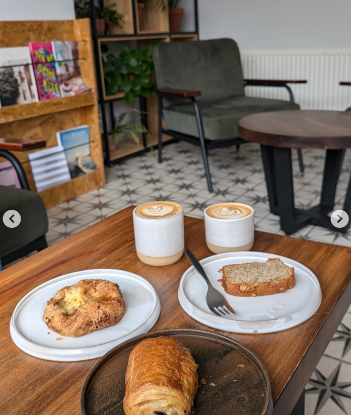 Shou's pale grey ceramic cups, pastries and cake on a wooden table inside the café